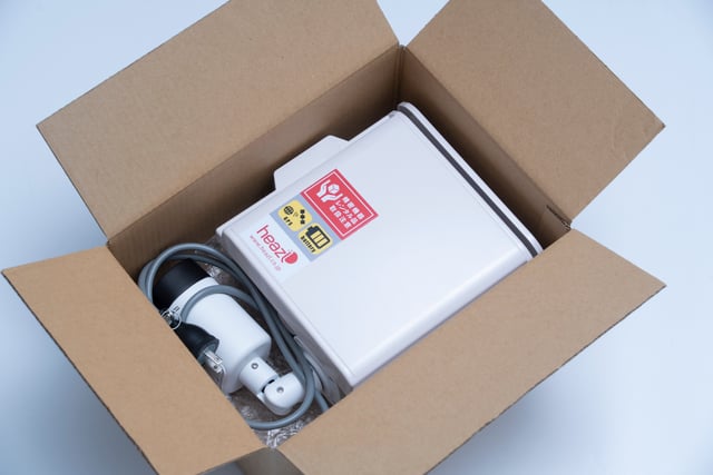 ワンタイムプランの監視カメラと電源ケーブルが段ボール箱に梱包された出荷時の状態